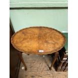 Oval topped pie crust edged side table in mixed woods on tapering spud feet