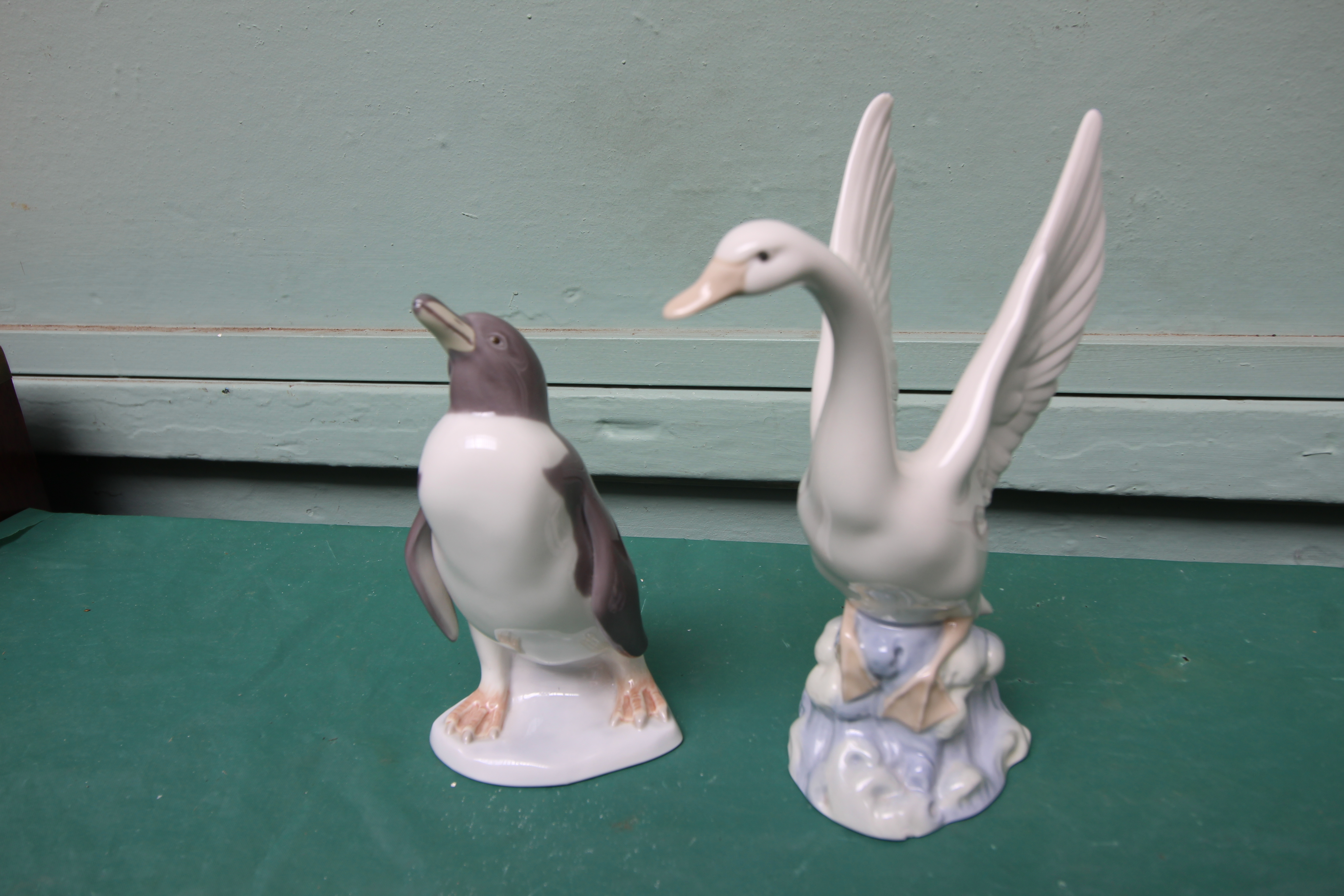 Lladro figure of a penguin and a Nao figure of an alighting swan