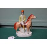 Staffordshire figure on oval plinth of a jockey mounted on a chestnut horse