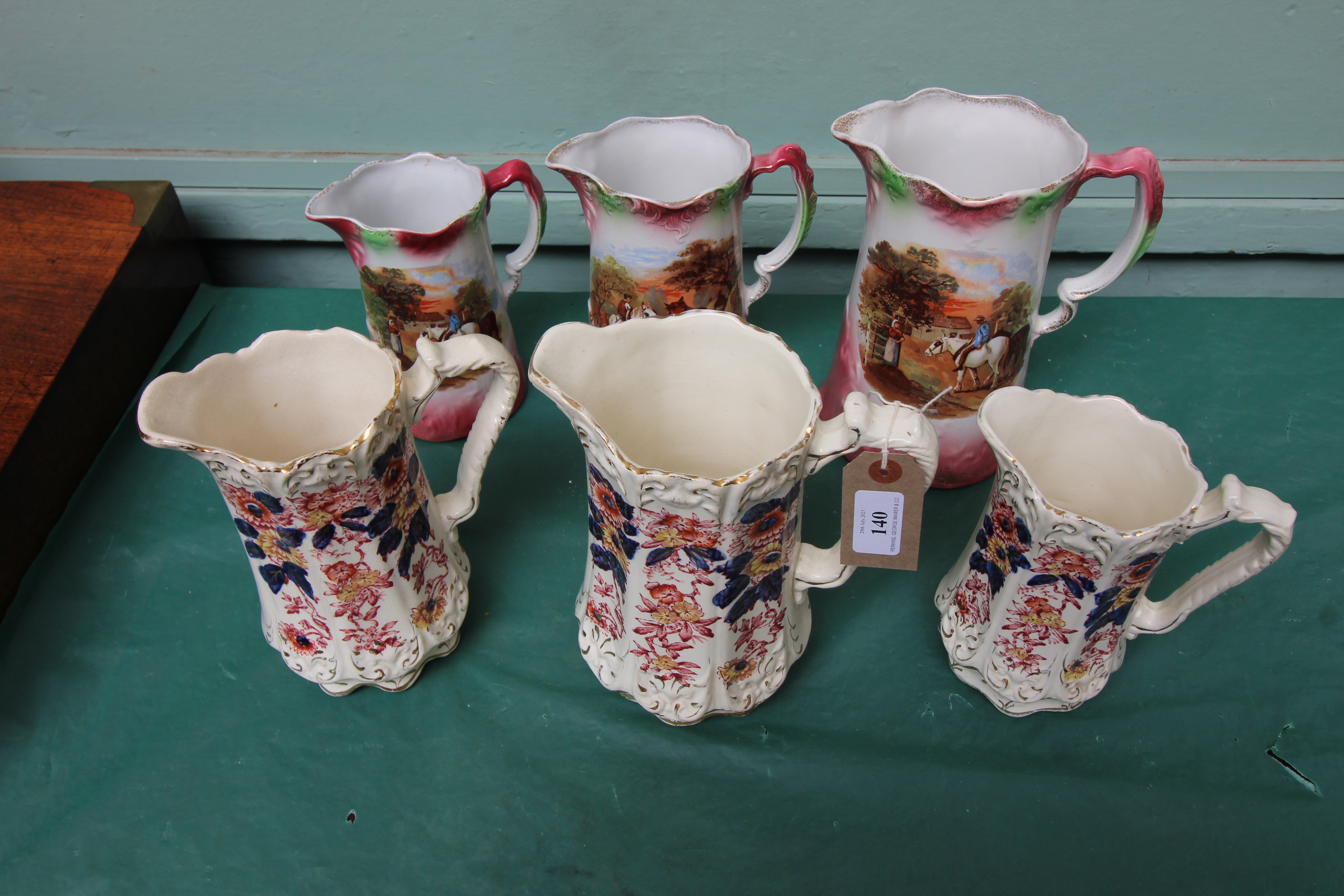 Set of three graduated jugs decorated richly multi coloured sprays and a further set of three