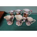 Set of three graduated jugs decorated richly multi coloured sprays and a further set of three