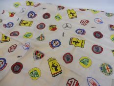 A Les Leston headscarf covered in classic car badges, folded.