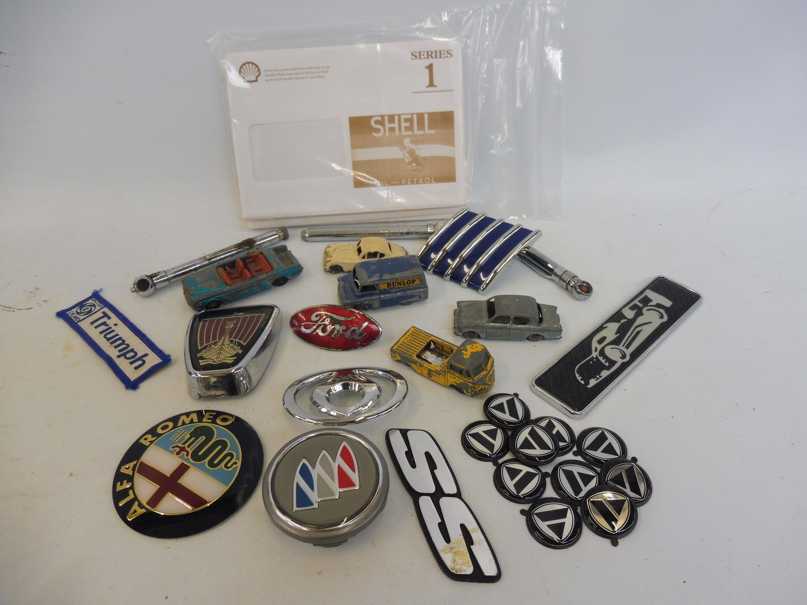 A mixed lot of badges, toy model cars, Shell advertising envelopes etc.