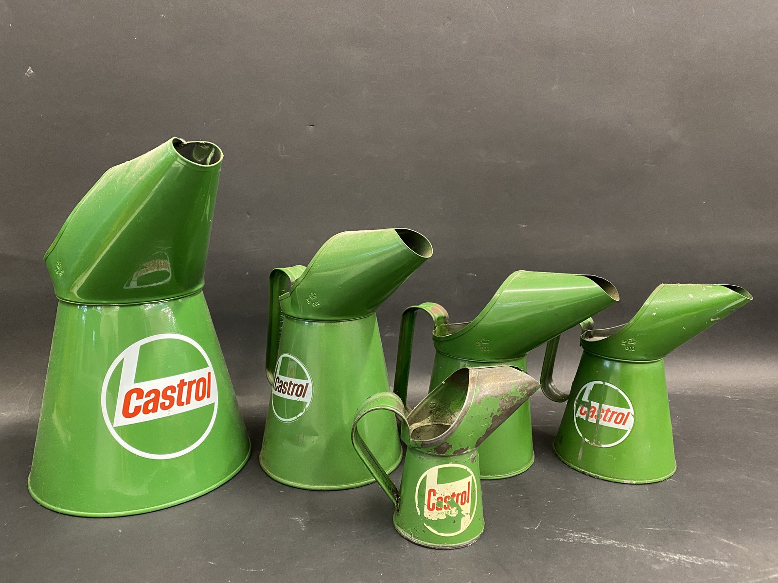 Four graduated contemporary Castrol oil measures and an earlier Castrol gill measure.