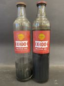 Two Shell X-100 Motor Oil quart glass bottles, with contents.