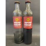 Two Shell X-100 Motor Oil quart glass bottles, with contents.