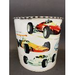 A waste paper bin decorated with Formula 1 race cars from the 1960s, 7" high.