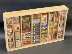 A collection of original lamp bulb packaging in a wooden display case including brands such as