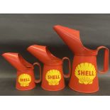 A graduated set of three Shell oil pourers from quart to half pint, appear new old stock.