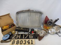A box of assorted car parts, including a radiator grille, spot lamps etc.