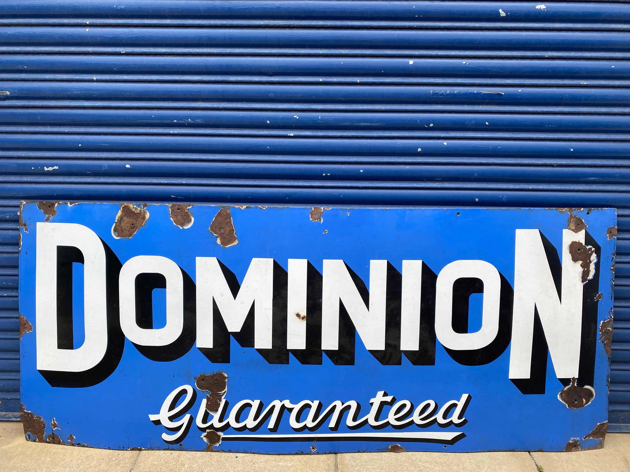 A Dominion Guaranteed rectangular enamel sign by Stocal, 72 x 30".