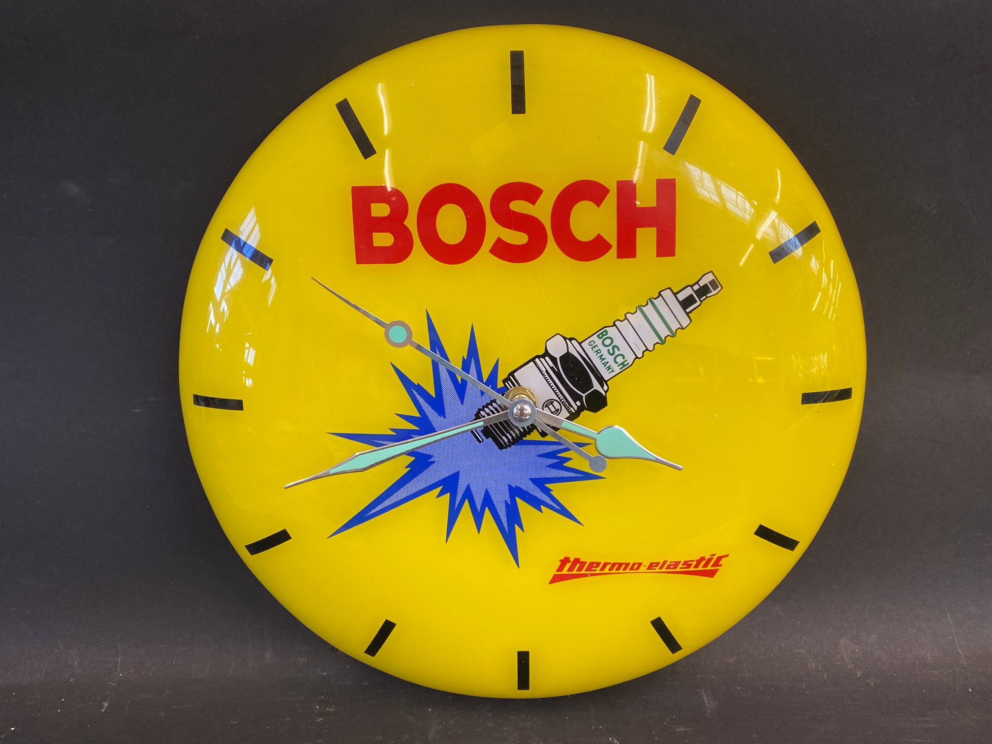 A Bosch spark plugs circular plastic battery operatied wall clock, 12" diameter.