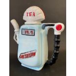 A decorative ceramic teapot in the shape of a petrol pump with globe.