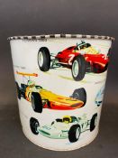 A waste paper bin decorated with Formula 1 race cars from the 1960s, 7" high.