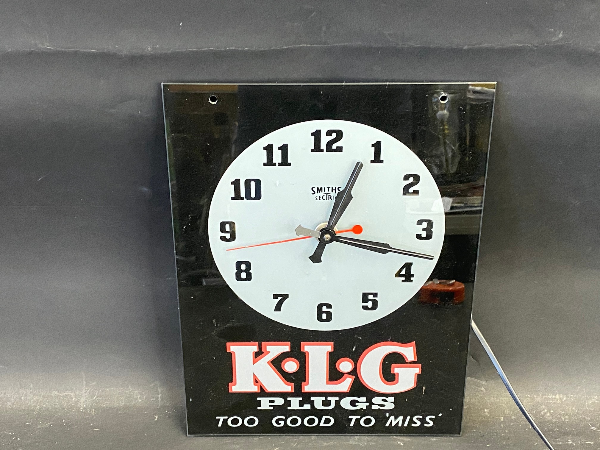 A K.L.G. Plugs Too Good To 'Miss' glass fronted Smiths Sectric advertising wall clock, 10 1/2 x