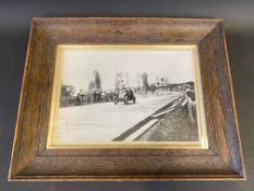 An oak framed and glazed black and white photograph of a veteran/Edwardian car racing, possibly a