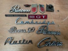 A tray of mostly 1980s car insignia and badges.