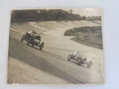 A photograph of a Mercedes racing a Bugatti type 35 racing at Brooklands on the banking, pencil
