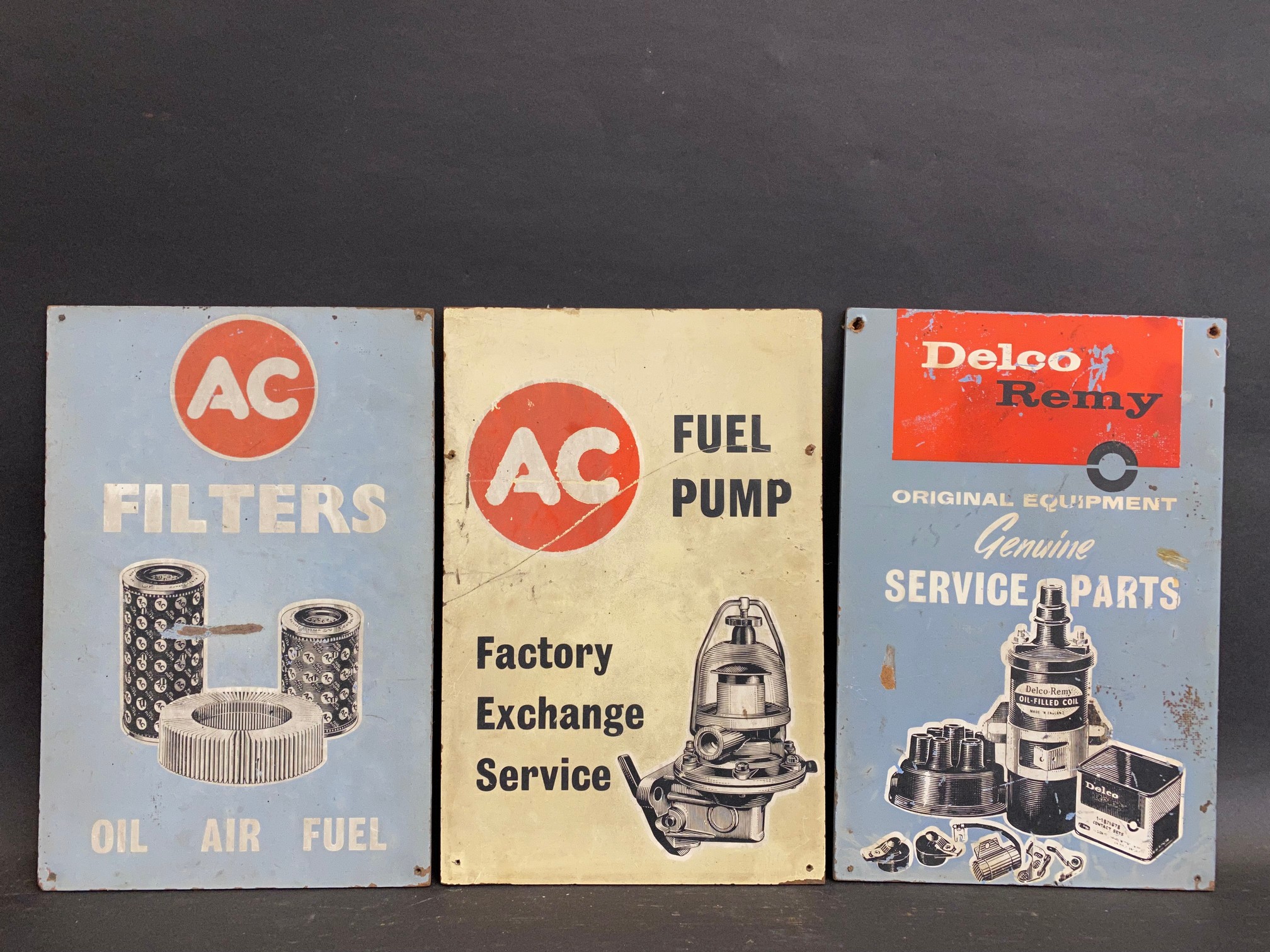 Three hardboard advertising sign, two for AC (filters and fuel pumps) and one for Delco Remy, all
