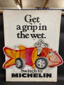 An unusual hardboard Michelin two piece advertising sign with an image of Mr. Bibendum sat astride a