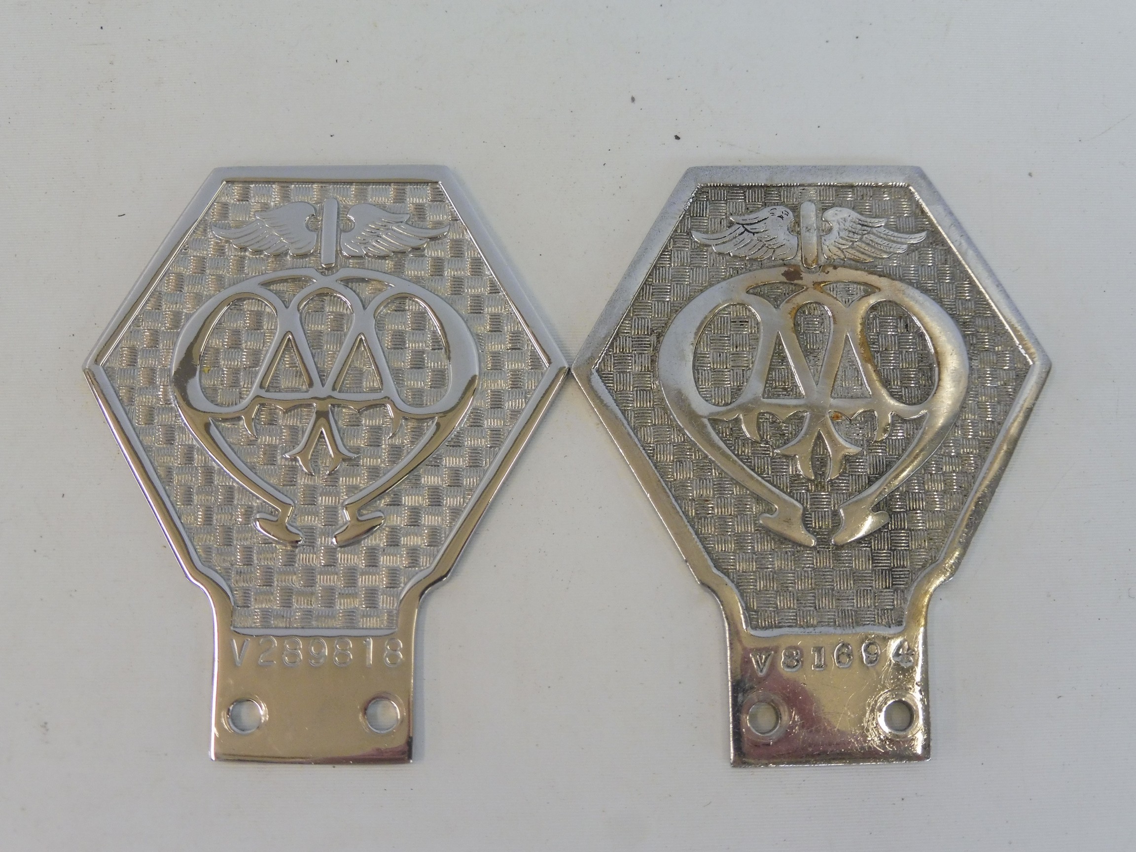 Two AA commercial large type 6 badges, thick and thin versions, stamped V81694 and V289818.