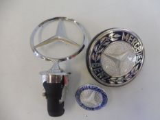A Mercedes-Benz bonnet/hood spring mascot badge plus two further badges.