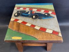 A childs wooden stool decorated with a racing car in relief.