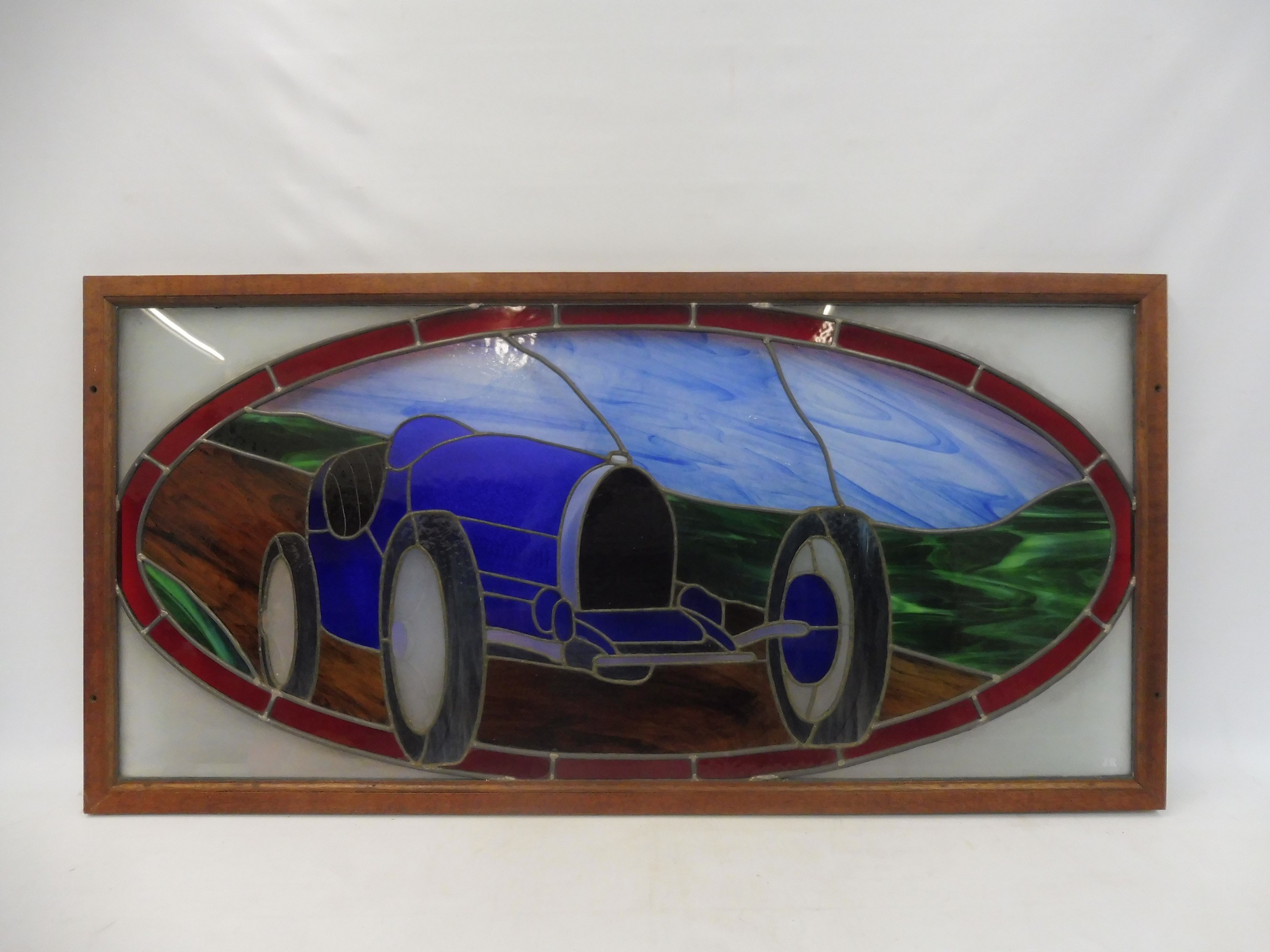 J. RAINEY - a stained glass panel showing a Bugatti Type 35, in a wooden frame, 47 1/2 x 23 1/2".