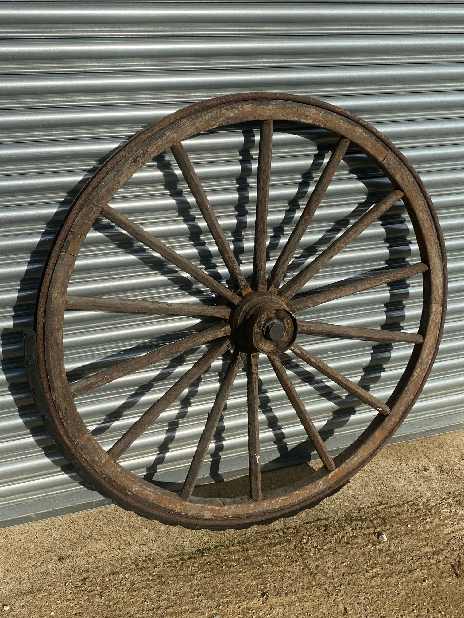 A large wooden and metal rimmed cart wheel with traces of original paint.