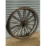 A large wooden and metal rimmed cart wheel with traces of original paint.