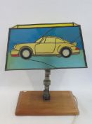 J. RAINEY - a stained glass lamp shade showing a Porsche, circa 1980s, supported by a camshaft