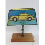 J. RAINEY - a stained glass lamp shade showing a Porsche, circa 1980s, supported by a camshaft