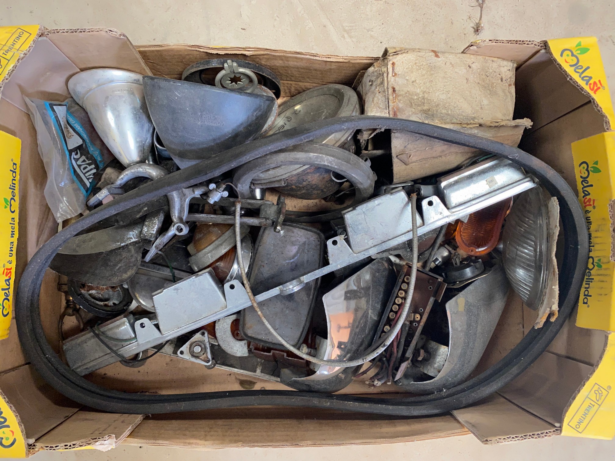 A box of assorted early car parts.