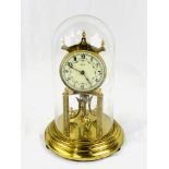 Brass anniversary clock under a glass dome, by Kieninger & Obergfell