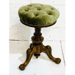 Green velvet upholstered circular stool with adjustable height.