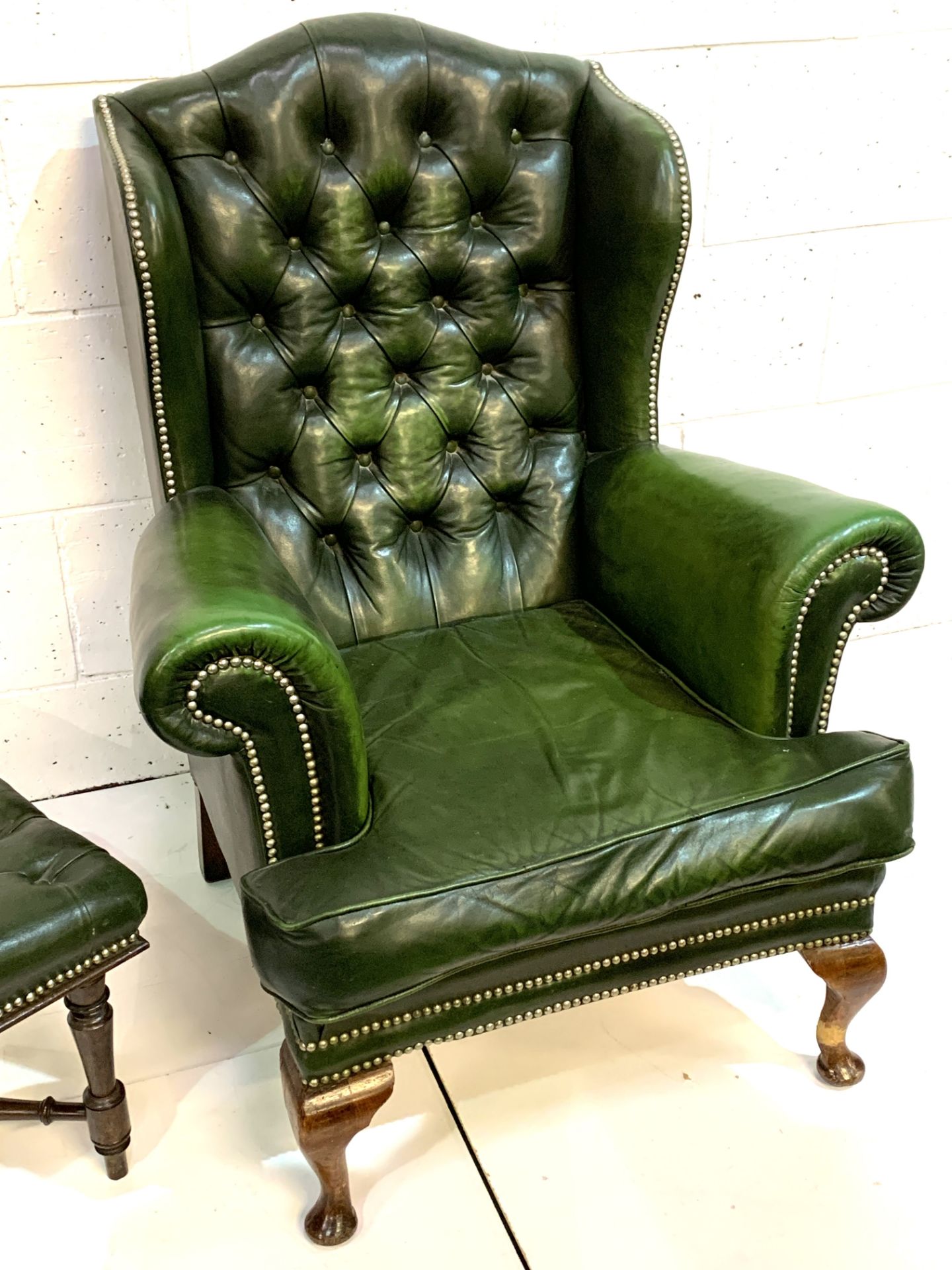 Green brass studded button back leather upholstered wing back armchair with a similar footstool. - Image 7 of 7