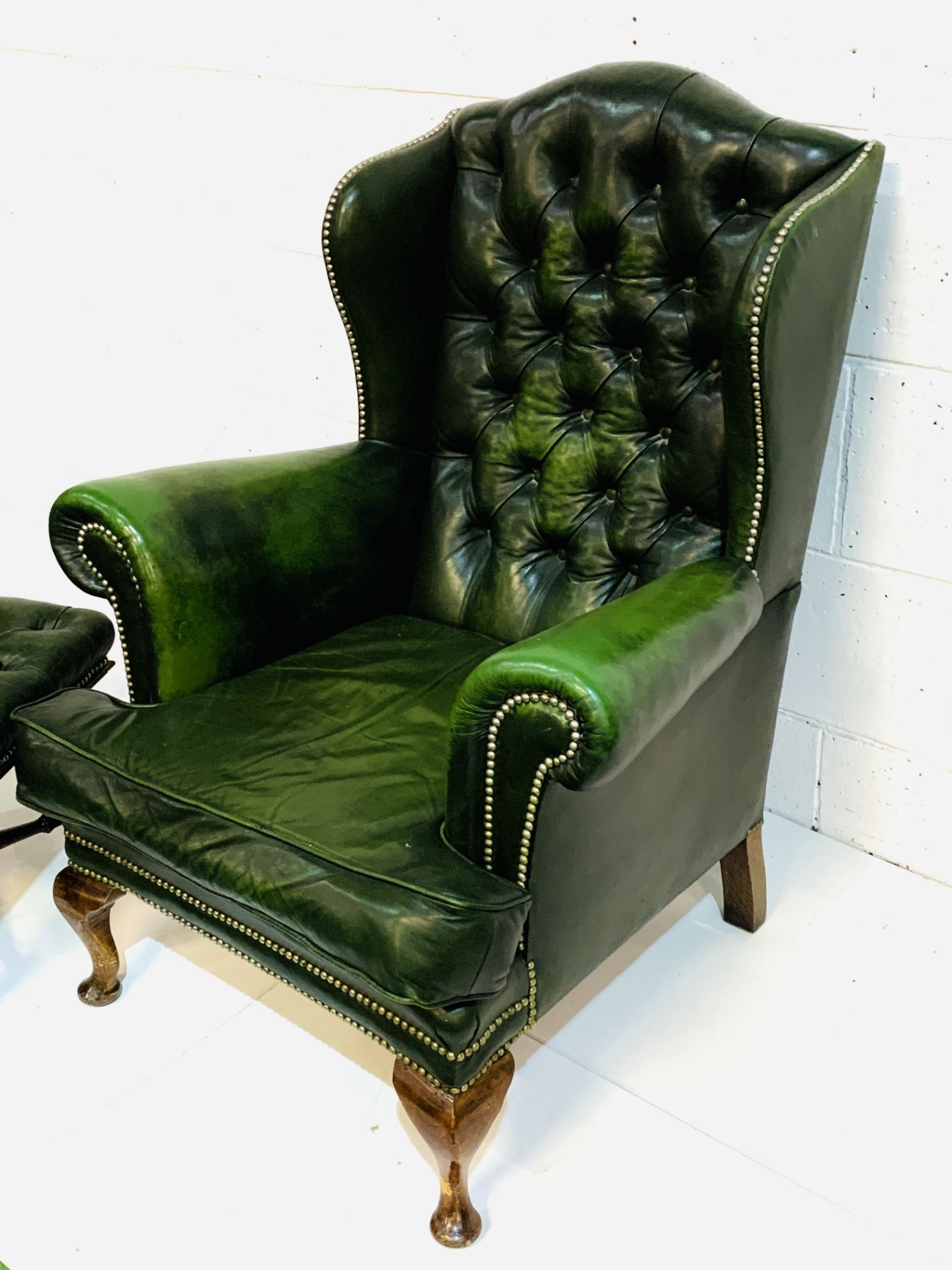 Green brass studded button back leather upholstered wing back armchair with a similar footstool. - Image 4 of 7