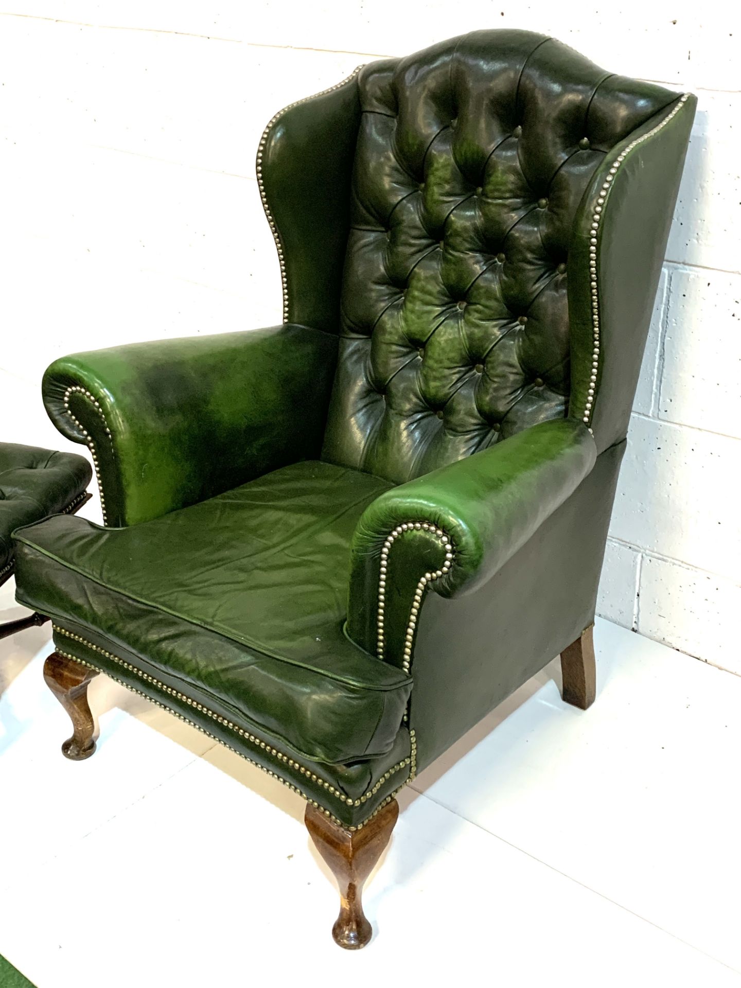 Green brass studded button back leather upholstered wing back armchair with a similar footstool. - Image 5 of 7