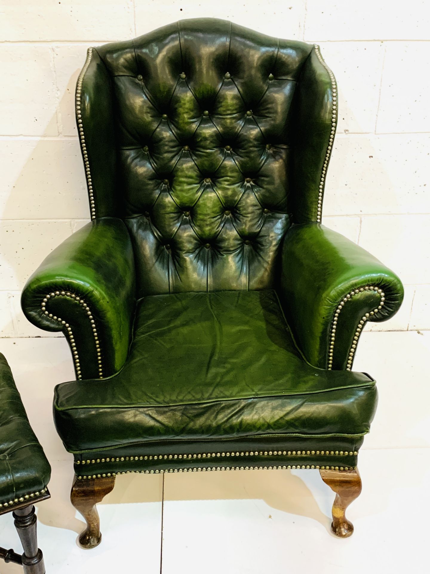 Green brass studded button back leather upholstered wing back armchair with a similar footstool. - Image 2 of 7