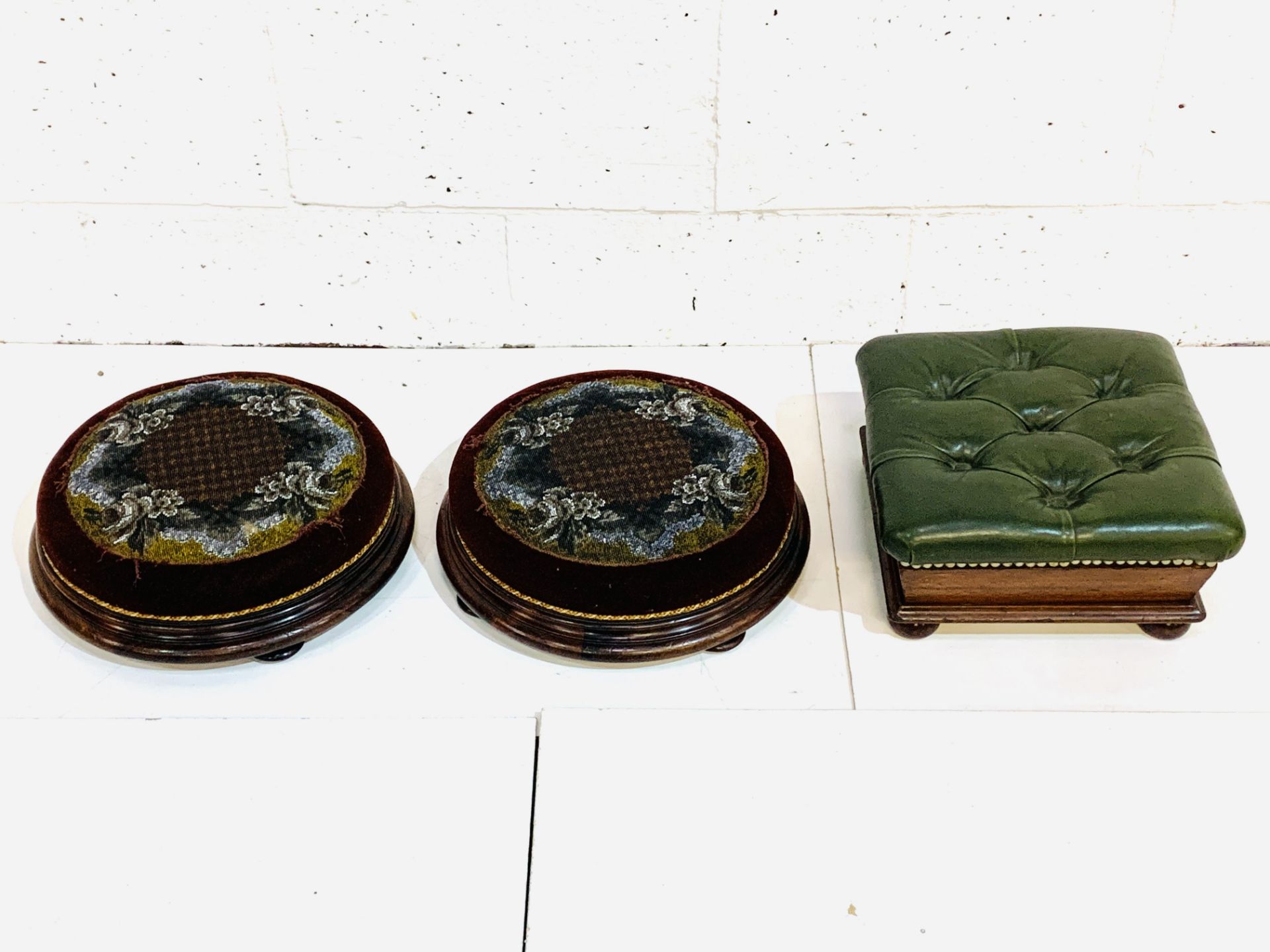 Two circular mahogany and tapestry top foot stools, and another footstool.