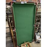 Pool table with cues and a set of balls.