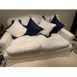 Cream upholstered two seat sofa with seat cushions and four scatter cushions.