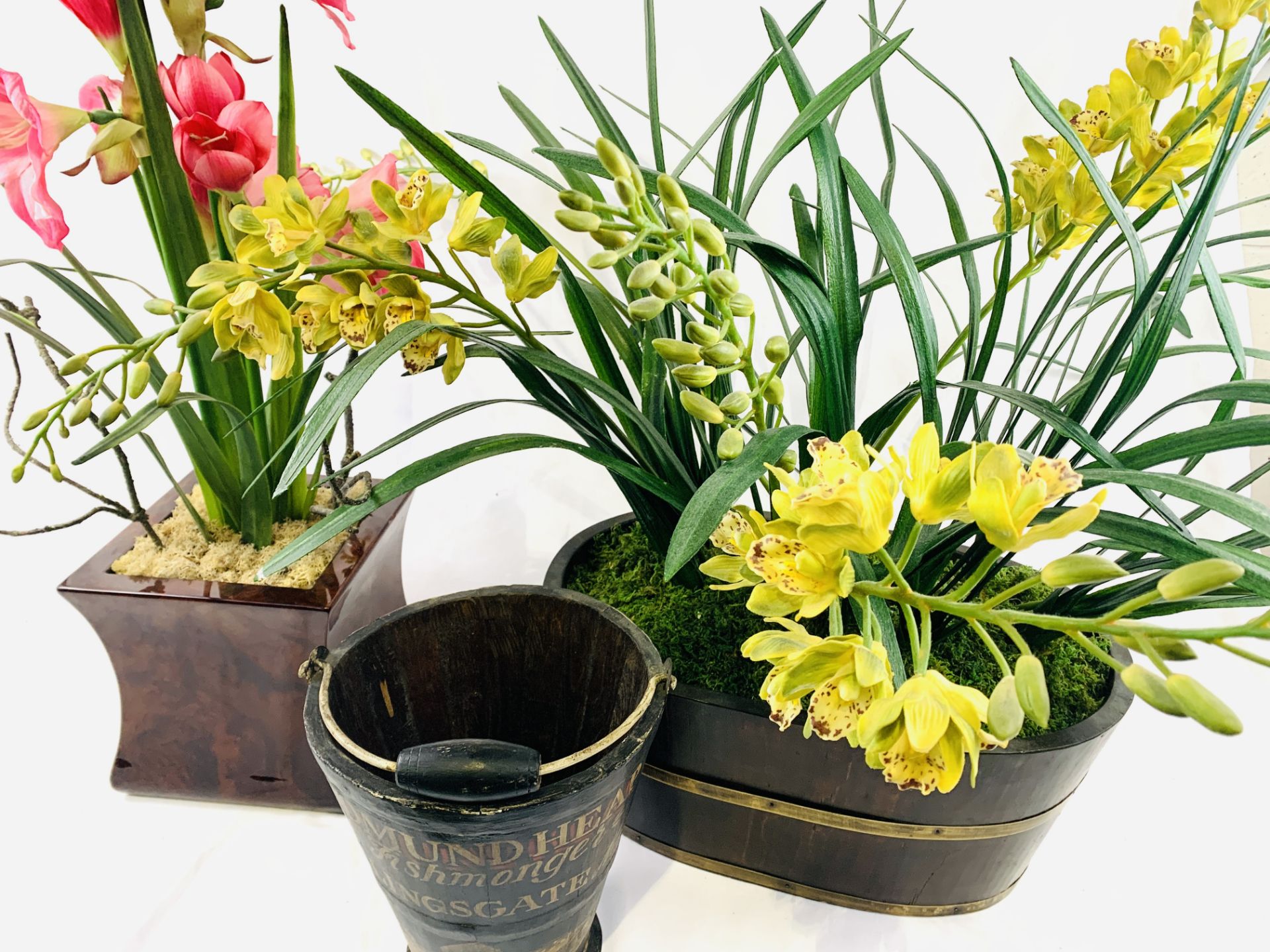 Two wood planters of lilies and orchids together with a decorative bucket.