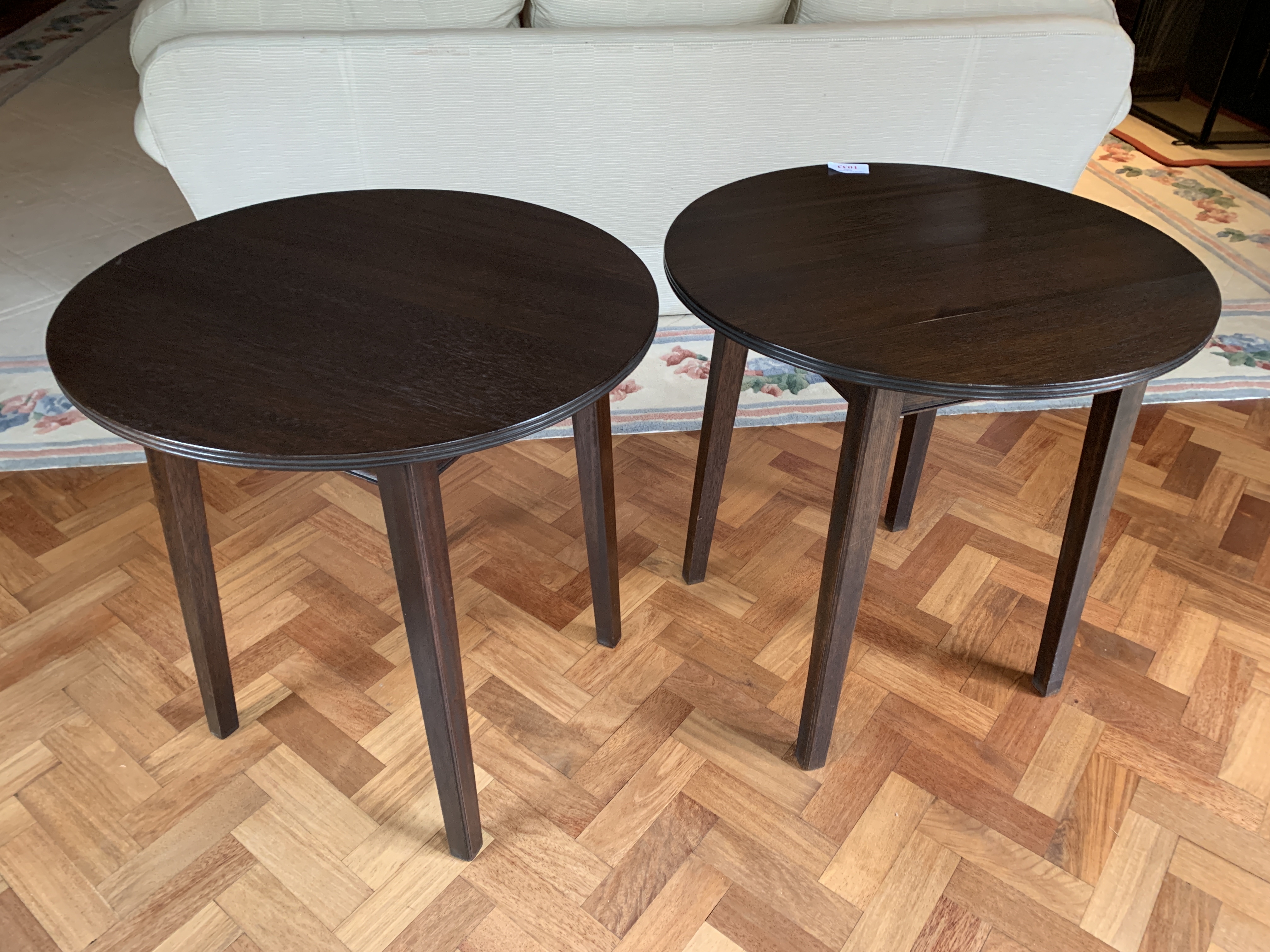 Two dark brown circular occasional tables on four block legs