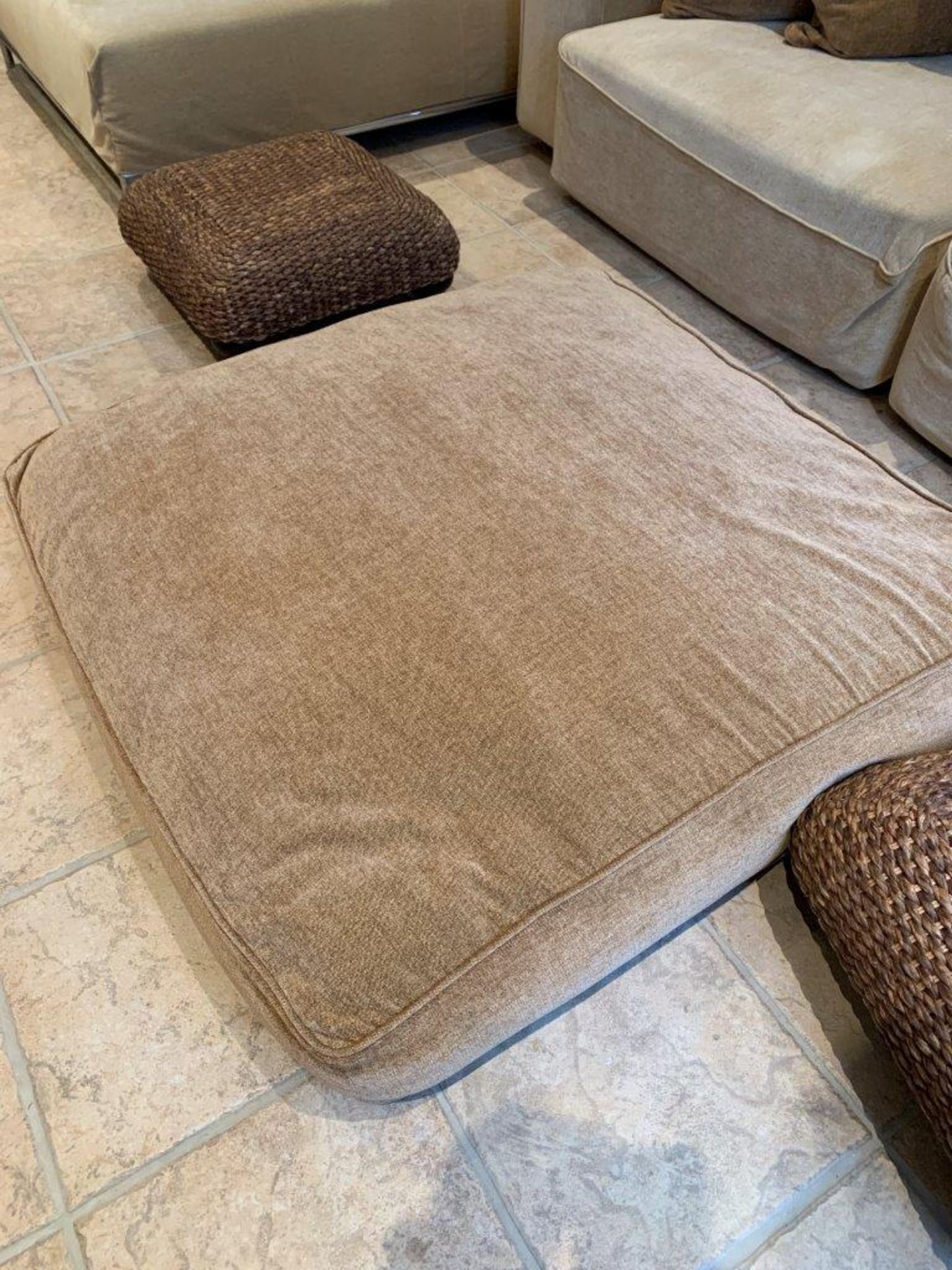 Light brown floor cushion and two rattan stools.
