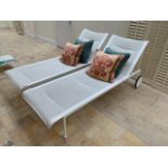Two white rattan style sun loungers with reclining backs