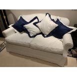 Cream upholstered two seat sofa with seat cushions and four scatter cushions.