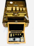 A fitted leather case containing a set of brass calibration weights