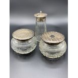 Two cut glass trinket pots with silver lids, and a cut glass tapered sugar caster with silver lid