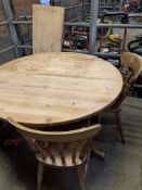 Circular pine extendable kitchen table together with three pine Windsor style chairs.